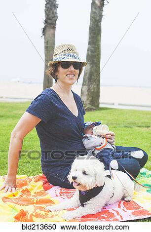 Stock Image - Mother and newborn baby sitting with dog in park. Fotosearch