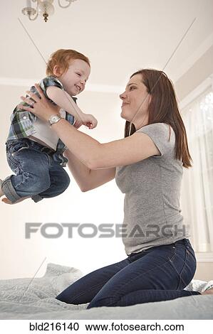 Stock Image - Mother and son playing on bed. Fotosearch