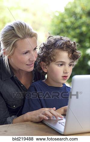 Stock Photo - Mother and son using laptop at table. Fotosearch
