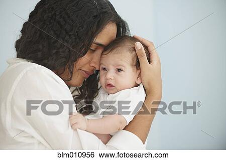 Stock Photograph - Mother cuddling baby girl. Fotosearch