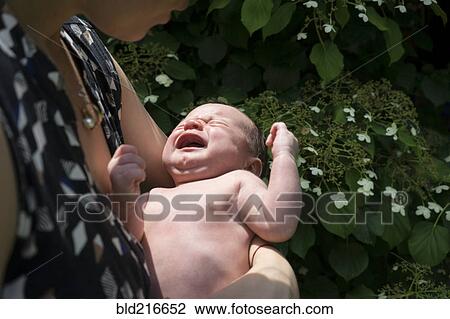 Stock Image - Mother holding crying baby in arms. Fotosearch