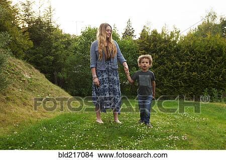 Mother holding hand of son in rural field View Large Photo Image Picture - Mother holding hand of son in rural field. Fotosearch