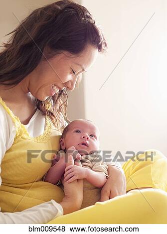 Stock Photo - Mother holding newborn baby in her lap. Fotosearch