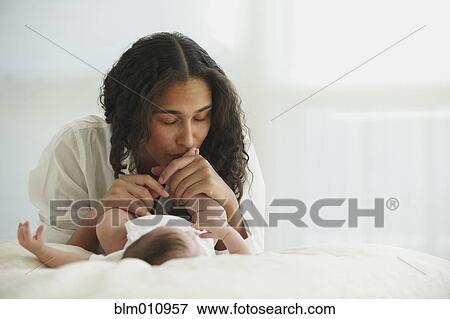 Stock Photo - Mother kissing baby girl's foot. Fotosearch