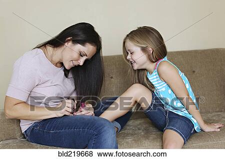 Mother painting toenails of daughter on sofa View Large Photo Image Stock Photo - Mother painting toenails of daughter on sofa. Fotosearch
