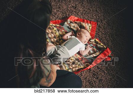 Stock Photo - Mother playing with baby daughter on blanket. Fotosearch