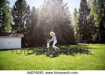 Stock Image - Mother playing with son in backyard. Fotosearch