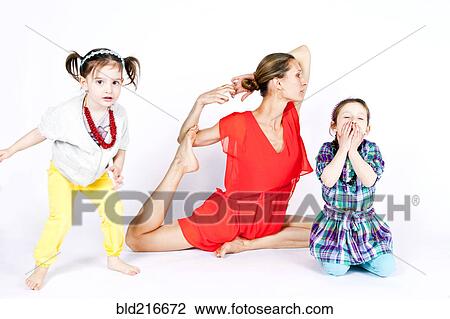 Stock Image - Mother practicing yoga with playful daughters. Fotosearch