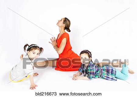 Mother practicing yoga with playful daughters View Large Photo Image Stock Image - Mother practicing yoga with playful daughters. Fotosearch