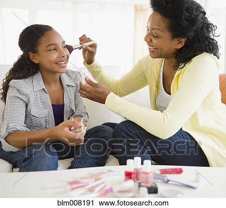 Stock Image - Mother putting makeup on daughter. Fotosearch