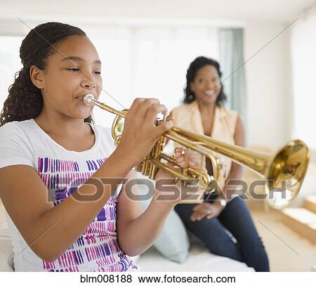 Stock Photo - Mother watching daughter playing trumpet. Fotosearch