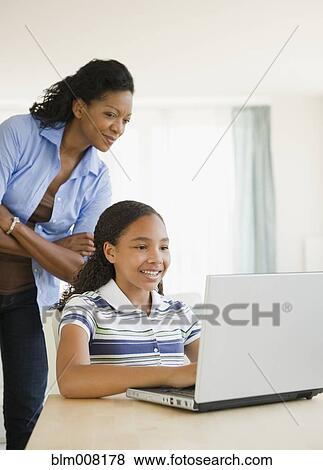 Mother watching daughter using laptop View Large Photo Image Stock Photo - Mother watching daughter using laptop. Fotosearch