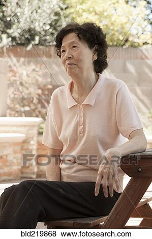 Older Asian woman sitting at picnic table View Large Photo Image Stock Photo - Older Asian woman sitting at picnic table. Fotosearch