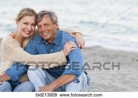 Stock Photo - Older Caucasian couple hugging on beach. Fotosearch