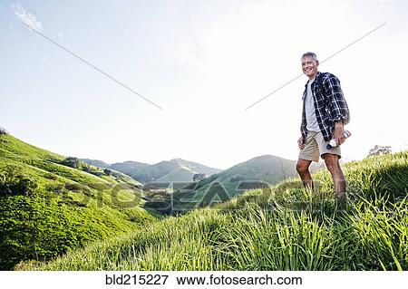 Stock Photo - Older Caucasian man smiling on grassy hillside. Fotosearch