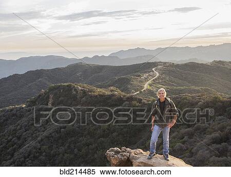 Stock Photography - Older Caucasian man standing on rocky hilltop. Fotosearch