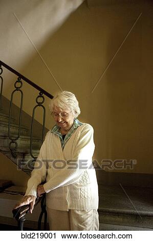 Stock Image - Older Caucasian woman climbing stairs. Fotosearch