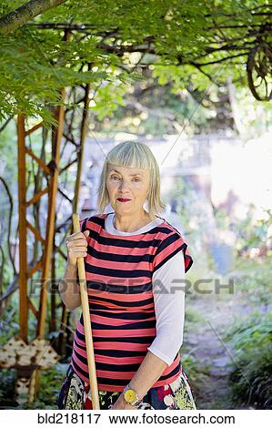 Stock Photo - Older Caucasian woman gardening in backyard. Fotosearch