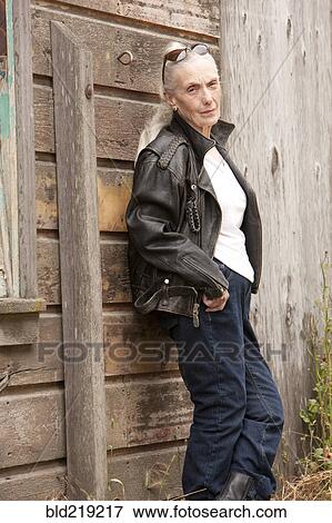 Stock Photo - Older Caucasian woman leaning on wooden wall. Fotosearch