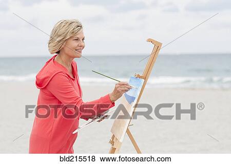 Older Caucasian woman painting on beach View Large Photo Image Stock Photo - Older Caucasian woman painting on beach. Fotosearch