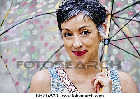 Stock Image - Older Caucasian woman posing with umbrella. Fotosearch
