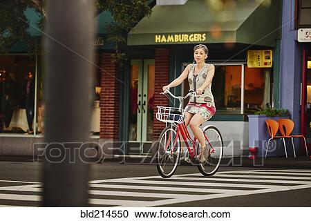 Stock Image - Older Caucasian woman riding bicycle in crosswalk. Fotosearch