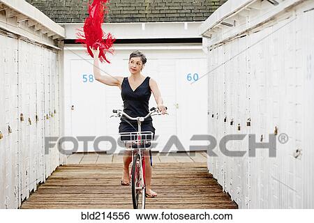 Stock Photograph - Older Caucasian woman riding bicycle on wooden dock. Fotosearch