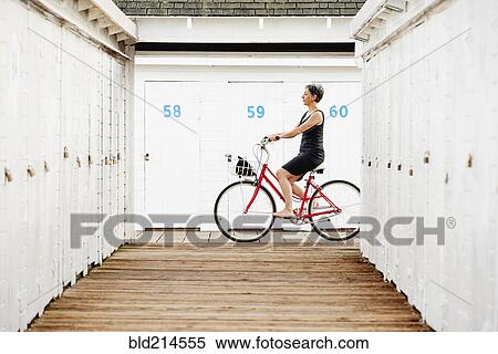 Stock Photography - Older Caucasian woman riding bicycle on wooden dock. Fotosearch