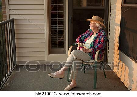 Stock Image - Older Caucasian woman sitting on porch. Fotosearch