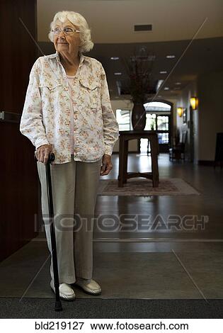 Stock Photo - Older Caucasian woman standing with cane in retirement home. Fotosearch