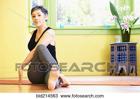 Stock Image - Older Caucasian woman stretching on floor. Fotosearch