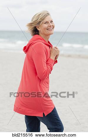 Stock Photograph - Older Caucasian woman walking on beach. Fotosearch
