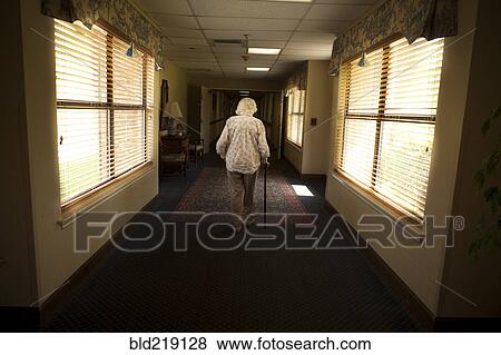 Stock Photo - Older Caucasian woman walking with cane in retirement home. Fotosearch