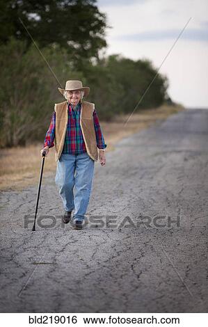 Older Caucasian woman walking with cane on rural road View Large Photo Image Stock Photograph - Older Caucasian woman walking with cane on rural road. Fotosearch