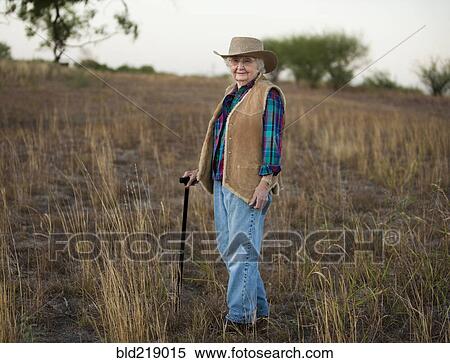 Stock Photography - Older Caucasian woman walking with cane in field. Fotosearch