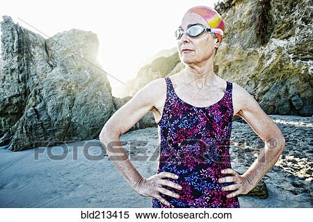 Stock Photography - Older Caucasian woman wearing goggles and swimsuit on beach. Fotosearch
