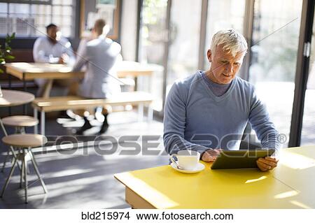 Older man using digital tablet in cafe View Large Photo Image Picture - Older man using digital tablet in cafe. Fotosearch