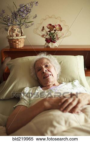 Stock Photography - Older mixed race woman laying in bed. Fotosearch