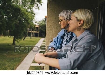 Older woman and granddaughter standing on balcony View Large Photo Image Stock Photograph - Older woman and granddaughter standing on balcony. Fotosearch