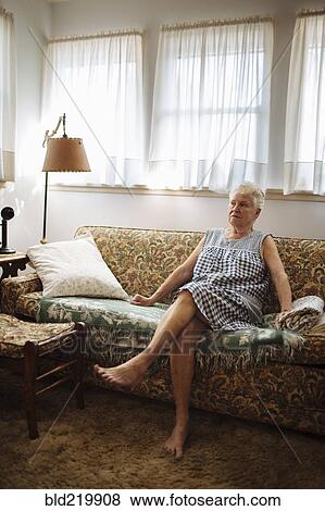 Stock Photo - Older woman sitting on sofa in living room. Fotosearch