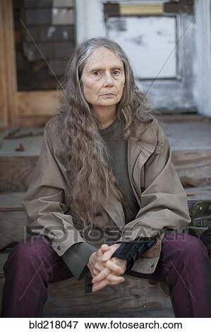Stock Photo - Older woman sitting on wooden front stoop. Fotosearch