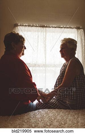 Stock Photography - Older woman sitting with daughter on bed. Fotosearch