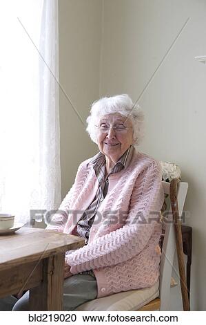 Stock Image - Older woman smiling at table. Fotosearch