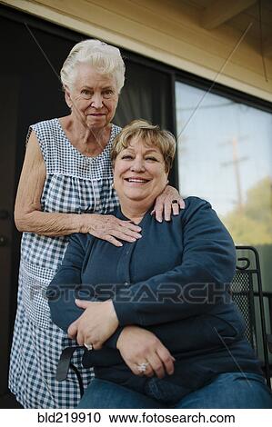 Stock Image - Older woman standing with daughter. Fotosearch