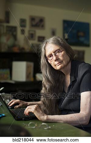 Picture - Older woman using laptop at desk. Fotosearch