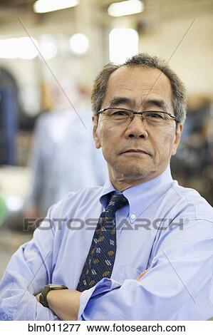 Stock Photo - Pacific Islander businessman standing in warehouse. Fotosearch