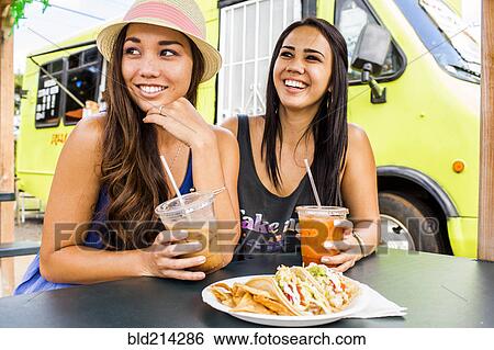 Stock Photograph - Pacific Islander women eating and drinking near food cart. Fotosearch