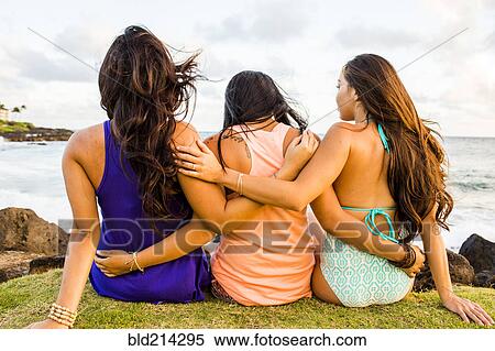 Stock Photography - Pacific Islander women hugging near beach. Fotosearch