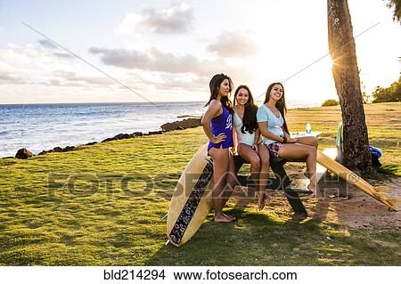 Picture - Pacific Islander women smiling on picnic table near beach. Fotosearch