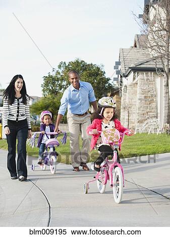 Stock Photography - Parents watching children ride bicycles. Fotosearch